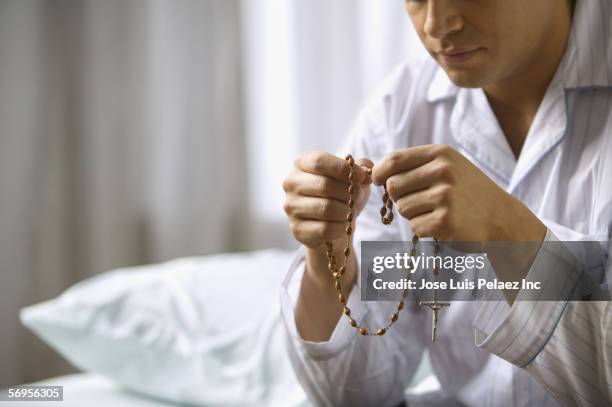 man in pajamas holding rosary - cross section stock-fotos und bilder