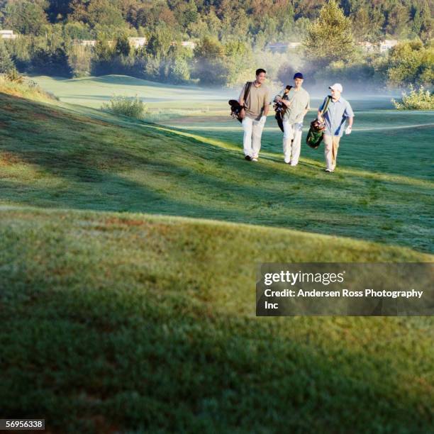 men walking on golf fairway - golf caddy stockfoto's en -beelden