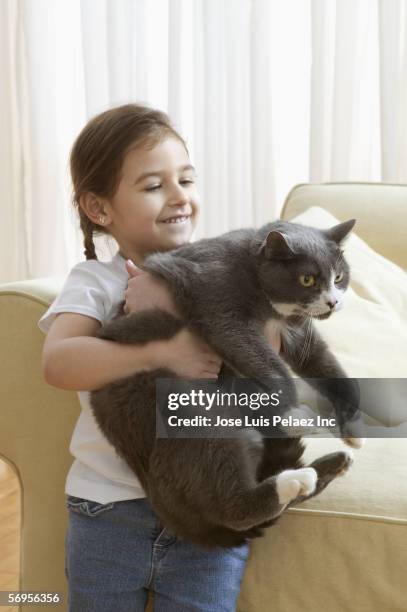 young girl carrying cat - girls cuddling cat stock-fotos und bilder