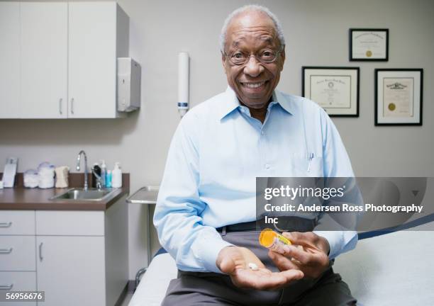 portrait of elderly man sitting in clinic taking medication - examination table stock pictures, royalty-free photos & images