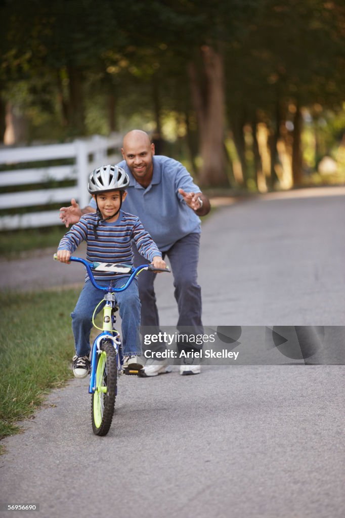 Father helping son learn how to ride bike