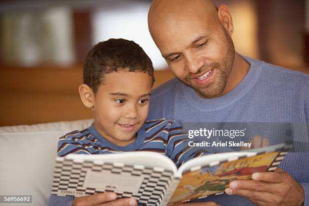 father and son reading book while sitting on couch - nursery rhymes stock pictures, royalty-free photos & images