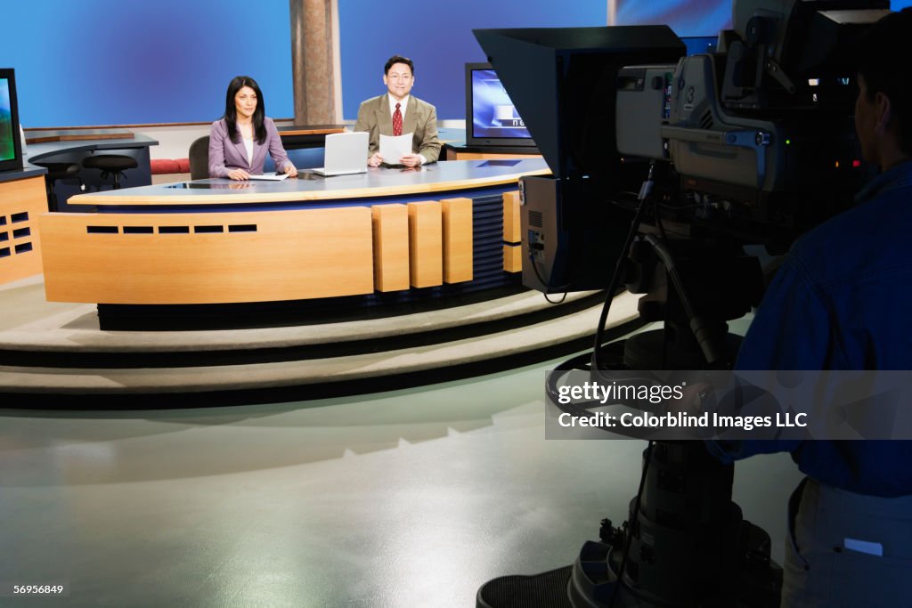 Anchor people on set in TV newsroom