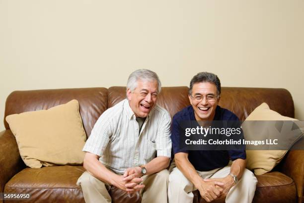 portrait of elderly men sitting on couch laughing - old brother stock pictures, royalty-free photos & images