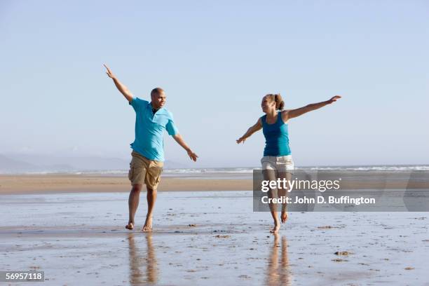 couple playing on beach with arms out - tillamook county fotografías e imágenes de stock