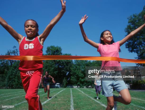 two girls crossing finish line at track - live finale stock pictures, royalty-free photos & images