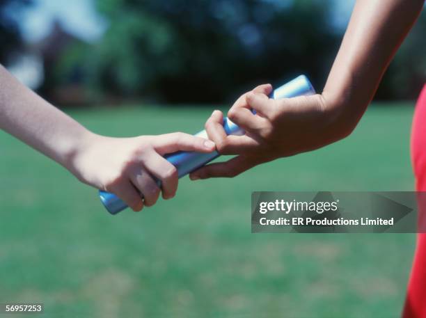 close up of hands exchanging baton - relay fotografías e imágenes de stock