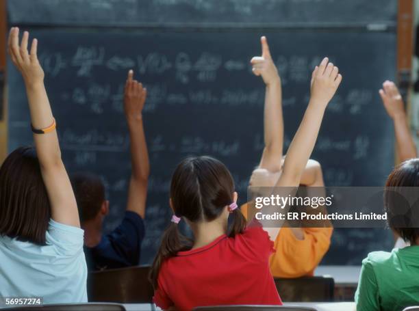 rear view of class raising hands - blackboard classroom stock-fotos und bilder