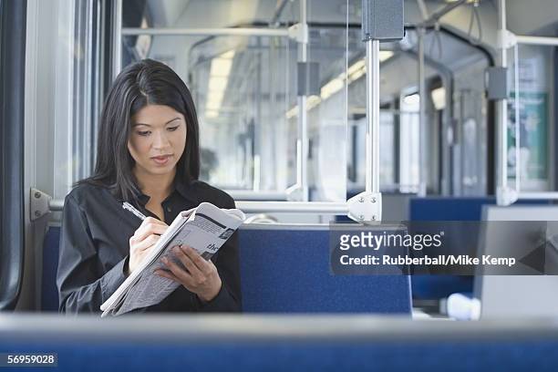woman working on a crossword puzzle on a commuter train - underground sign 個照片及圖片檔