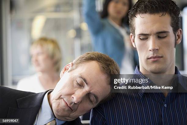 close-up of a mature man asleep on a young man's shoulder - two people on bus foto e immagini stock