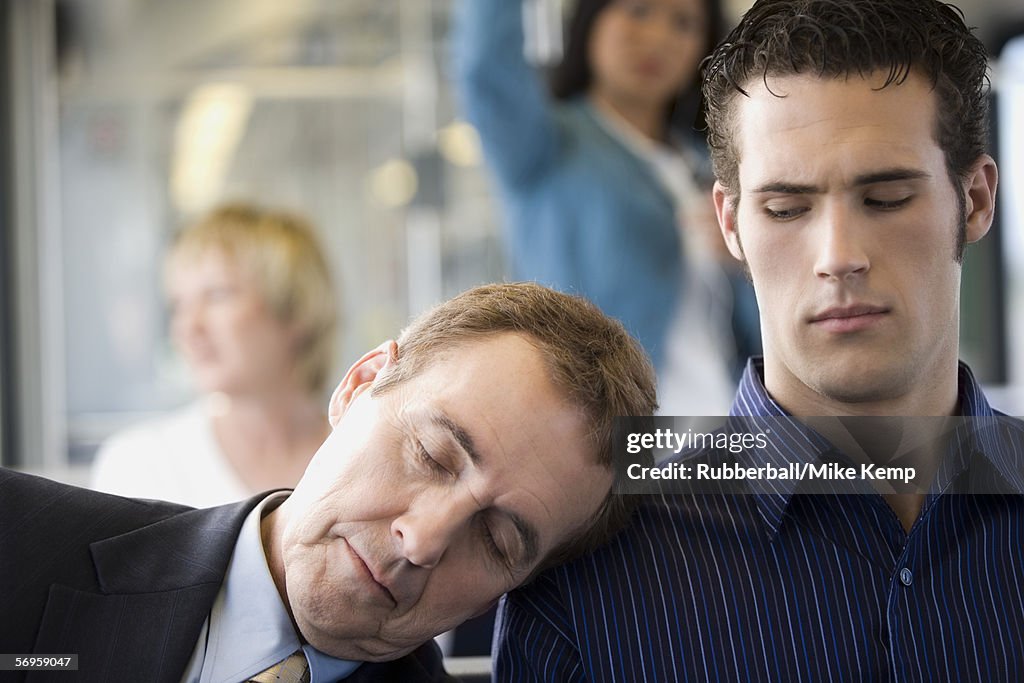 Close-up of a mature man asleep on a young man's shoulder