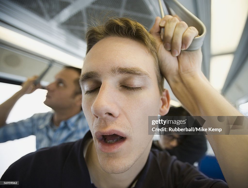 Close-up of a young man sleeping on a commuter train