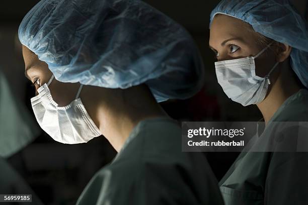 profile of two surgeons in an operating room - surgical mask profile stock pictures, royalty-free photos & images