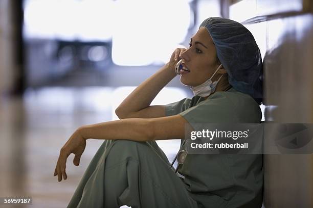 profile of a female surgeon talking on a mobile phone - surgical mask profile stock pictures, royalty-free photos & images