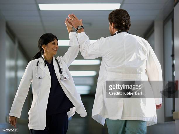rear view of a male doctor giving high-five to a female doctor - a celebration of arts education stockfoto's en -beelden