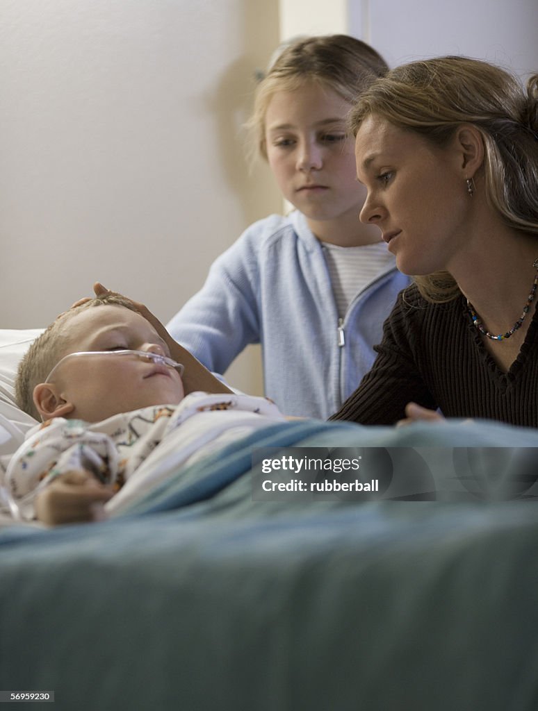 Mother and her daughter looking at her son in the hospital