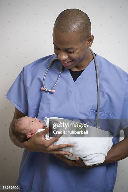 male doctor carrying a new born baby - black premature babies stock pictures, royalty-free photos & images