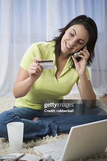 mid adult woman talking on a mobile phone holding a credit card - alfombra raton fotografías e imágenes de stock