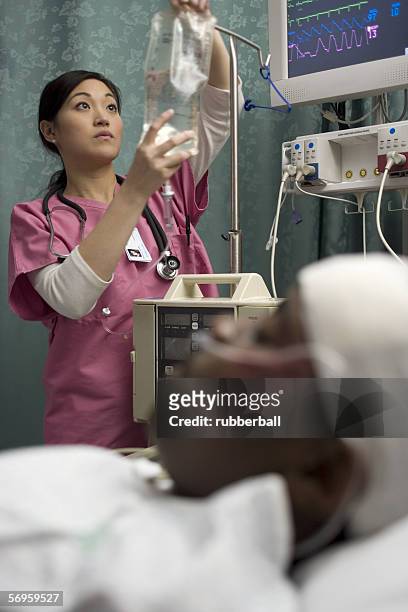 female nurse checking an intravenous drip - patients brothers 個照片及圖片檔