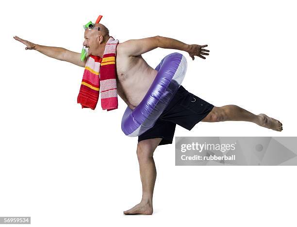 man standing on one leg with an inflatable ring around his waist - snorkel white background stock-fotos und bilder