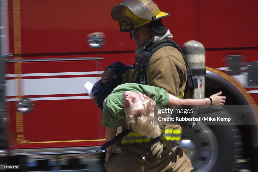 Profile of a firefighter carrying a boy