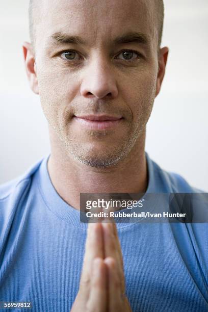 portrait of a mid adult man standing in a prayer position - prayer pose greeting stock-fotos und bilder