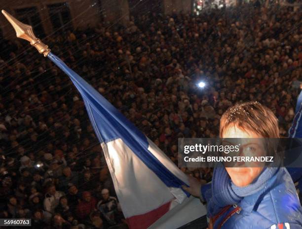 French gold medalist Florence Baverel-Robert holds her national flag in front of the crowd, 28 February 2006 in Pontarlier, eastern France, upon her...