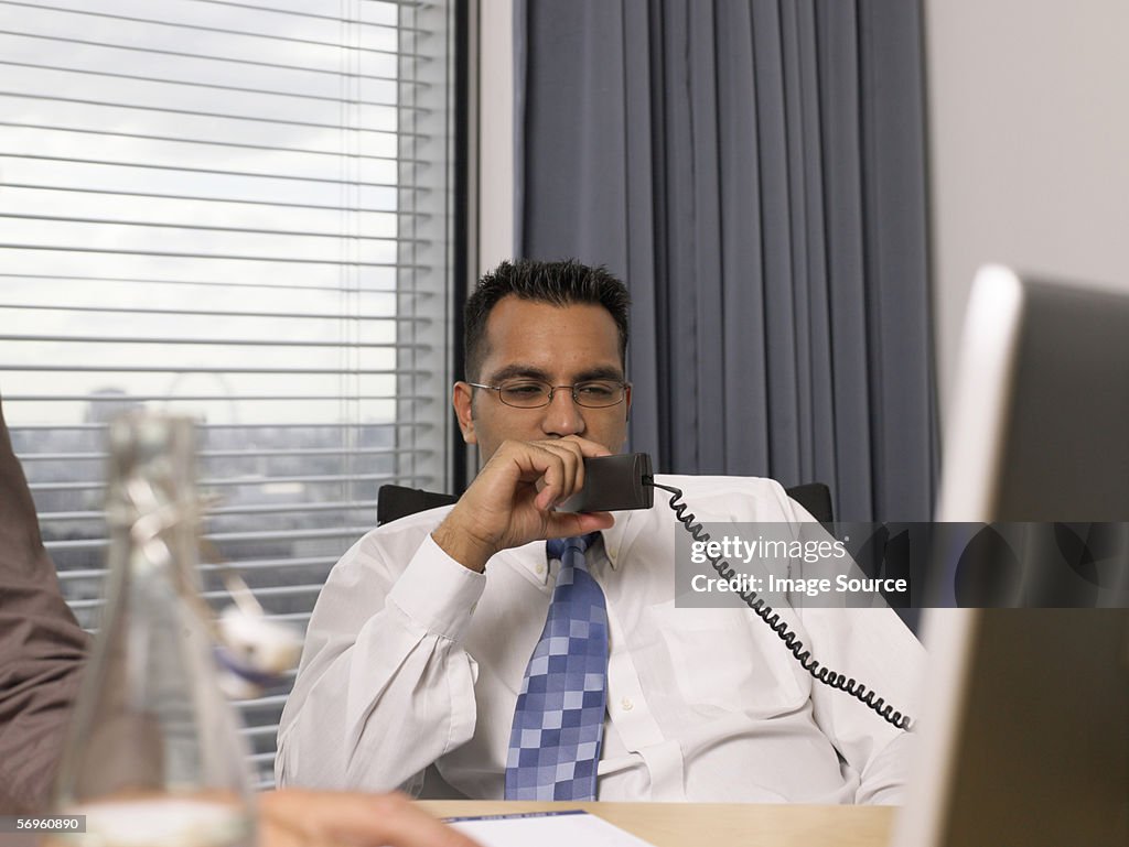Serious looking businessman holding a telephone