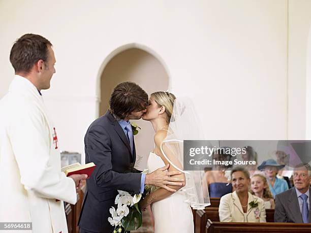 Newlyweds kissing while exiting the church after wedding ceremony, family  and friends celebrating their love with the shower of soap bubbles, custom  Stock Photo - Alamy