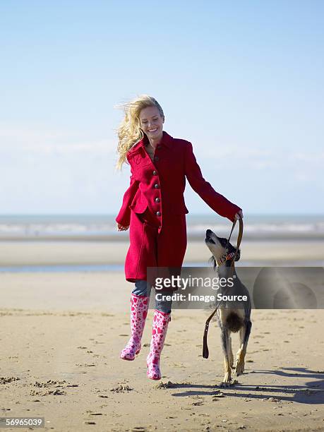 frau springen mit hund am strand - dog jump stock-fotos und bilder