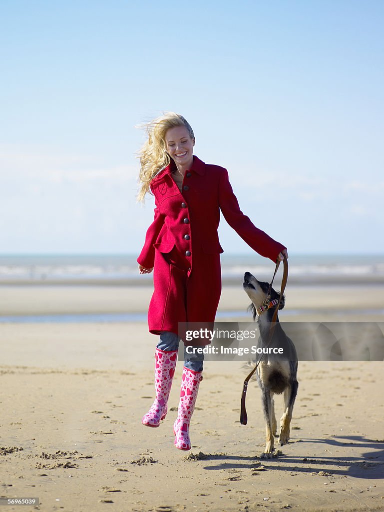 Woman skipping with dog on beach