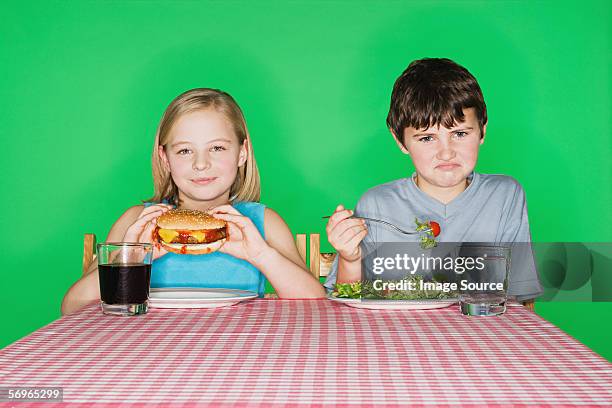 girl with a burger and boy with a salad - jealous sister stock pictures, royalty-free photos & images