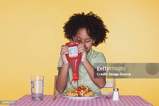 girl squeezing ketchup onto curly fries - salt shaker stock pictures, royalty-free photos & images
