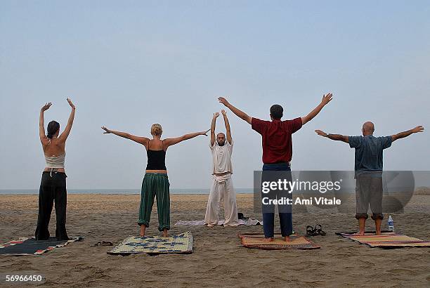 Foreign tourists and travelers learn yoga on the beach on February 27, 2006 in Arambol, Goa, India. The tiny Indian state became known as a hippie...