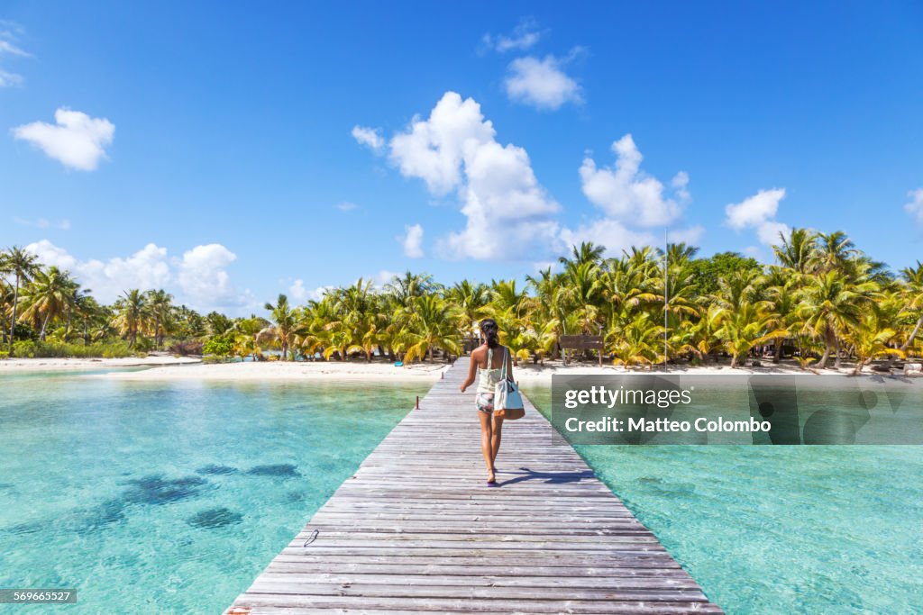 Tourist walking on jetty to tropical island