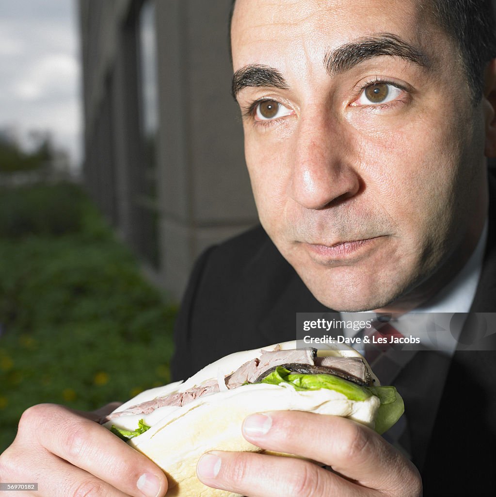 Close up portrait of businessman eating sandwich