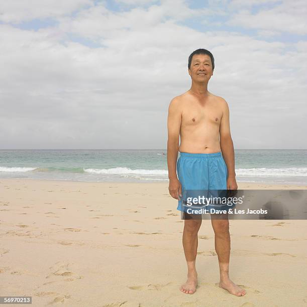 man in swimming trunks at beach - asian man barefoot foto e immagini stock