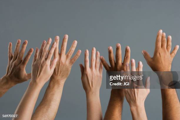 close up of group of hands raised - man with arms raised stock pictures, royalty-free photos & images