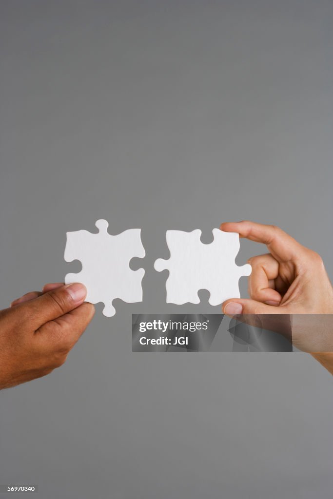 Close up of two hands holding puzzle pieces