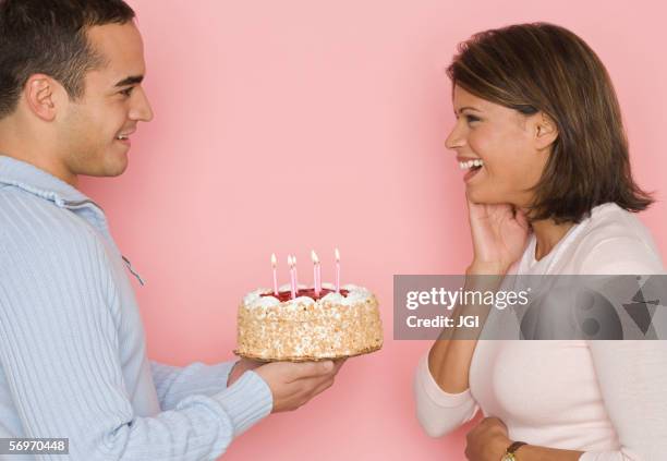 profile of man holding cake and looking at woman - man giving cake candle stock pictures, royalty-free photos & images