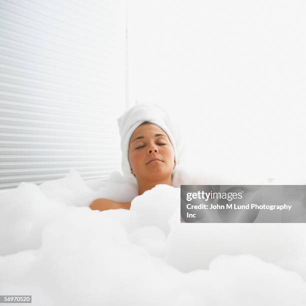 woman with eyes closed in bubble bath with towel on head - woman bath bubbles stock-fotos und bilder