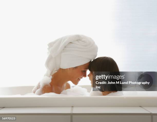 profile of mother and daughter touching foreheads in bubble bath - mother daughter towel fotografías e imágenes de stock
