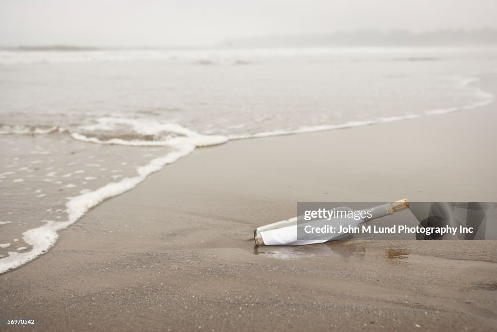 Bottle with message in sand at beach