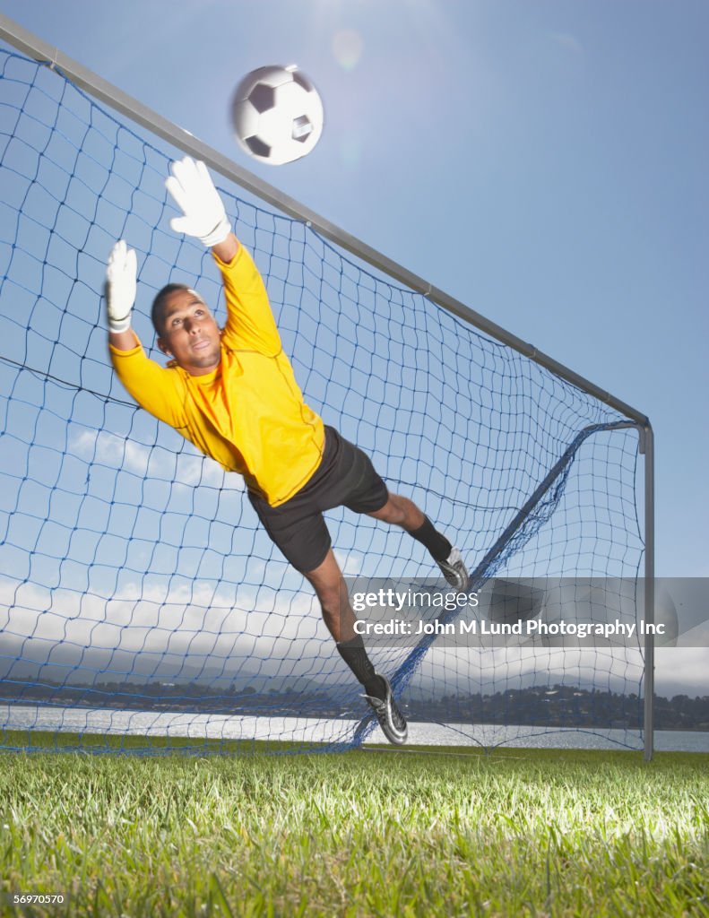 Goalie jumping to block soccer ball
