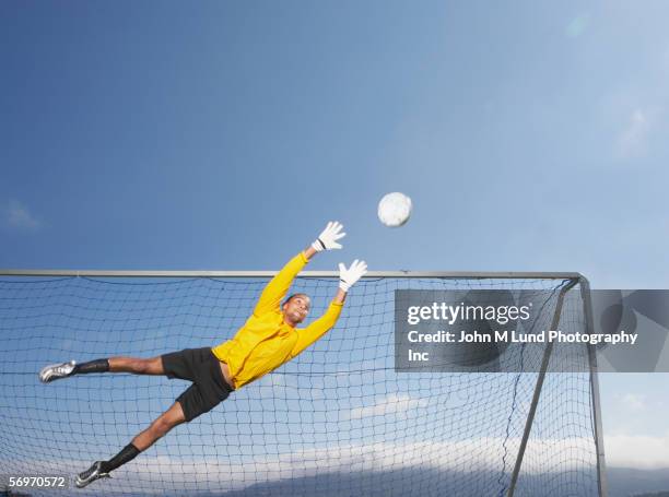 goalie jumping to block soccer ball - diving to the ground bildbanksfoton och bilder