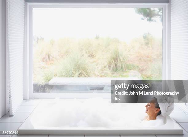 senior woman in bubble bath with towel wrapped around her head - woman bath bubbles stock-fotos und bilder