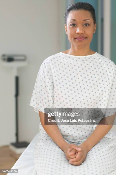 female patient wearing gown sitting in examination room - patient gown stock pictures, royalty-free photos & images