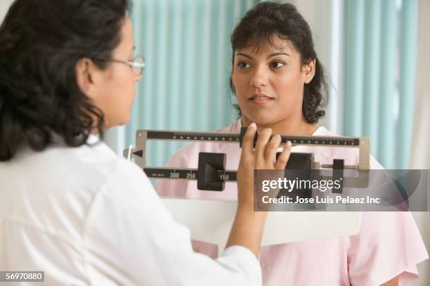 doctor weighing female patient on scale - puerto rican ethnicity stock pictures, royalty-free photos & images