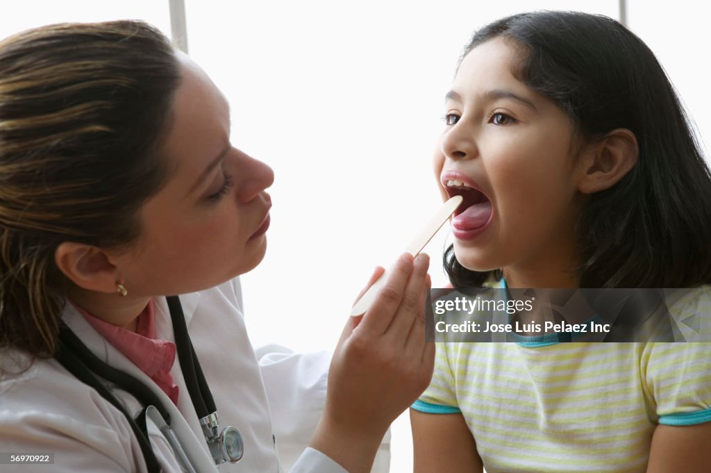 Female doctor checking girl's tonsils