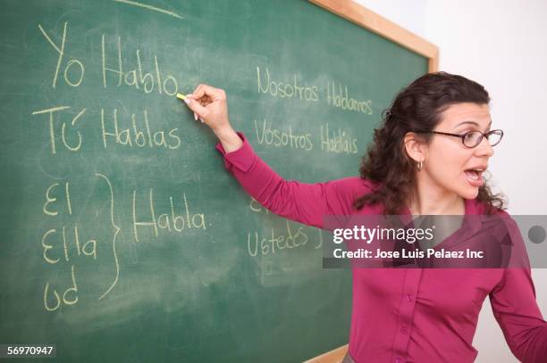 teacher writing on chalkboard while talking - teacher board stock pictures, royalty-free photos & images